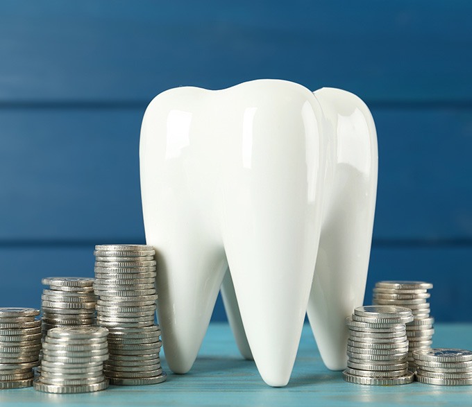 A large ceramic tooth surrounded by coins