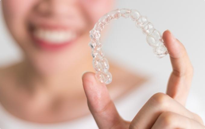 Close up of person holding an Invisalign clear aligner