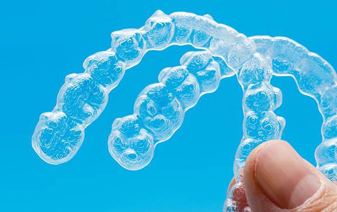 Person holding two Invisalign aligners