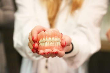 dentist smiling and holding dentures 