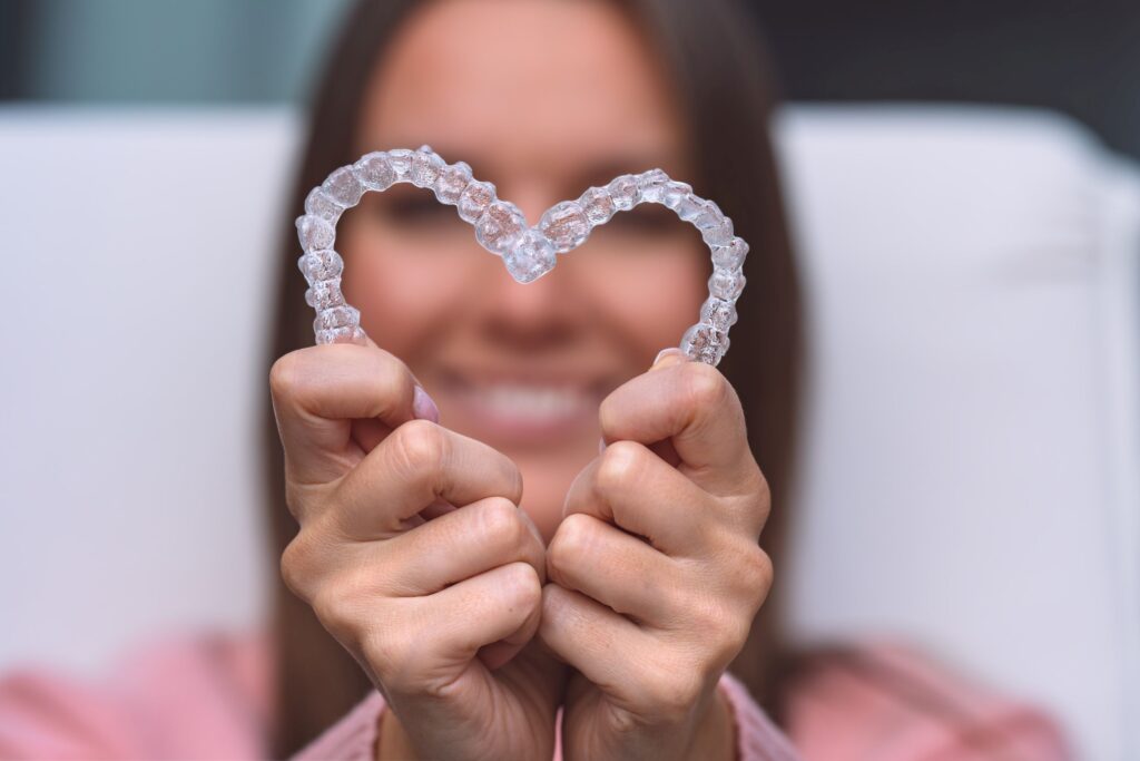 Woman holding Invisalign trays in the shape of a heart