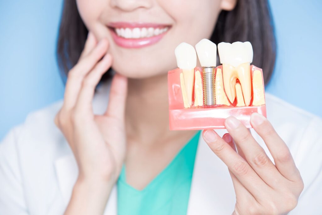 Dentist holding sample implant in one hand and touching her jaw with the other